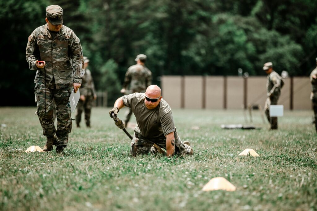 A group of soldiers engaged in a rigorous outdoor military training session in a grassy field.